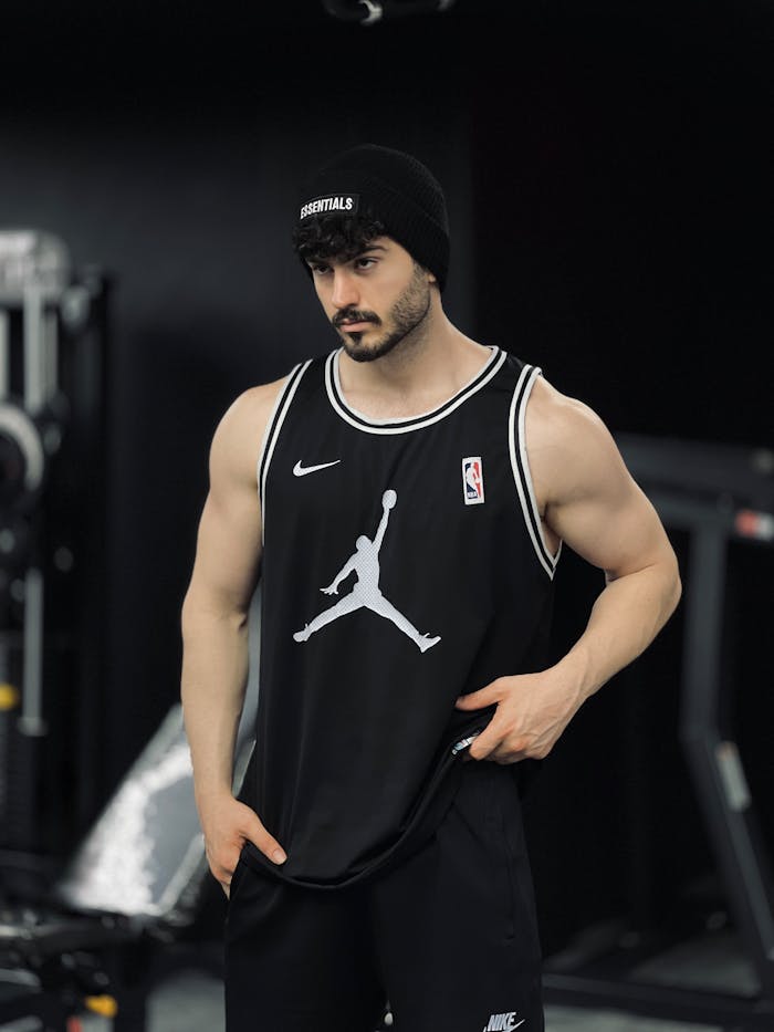 Muscular man in gym attire showcasing strength and fitness indoors.