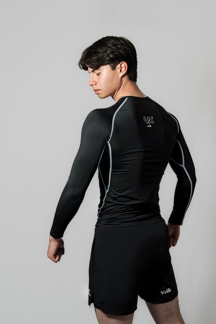 Athletic young man in black sportswear, poised and confident, showcasing fitness apparel.